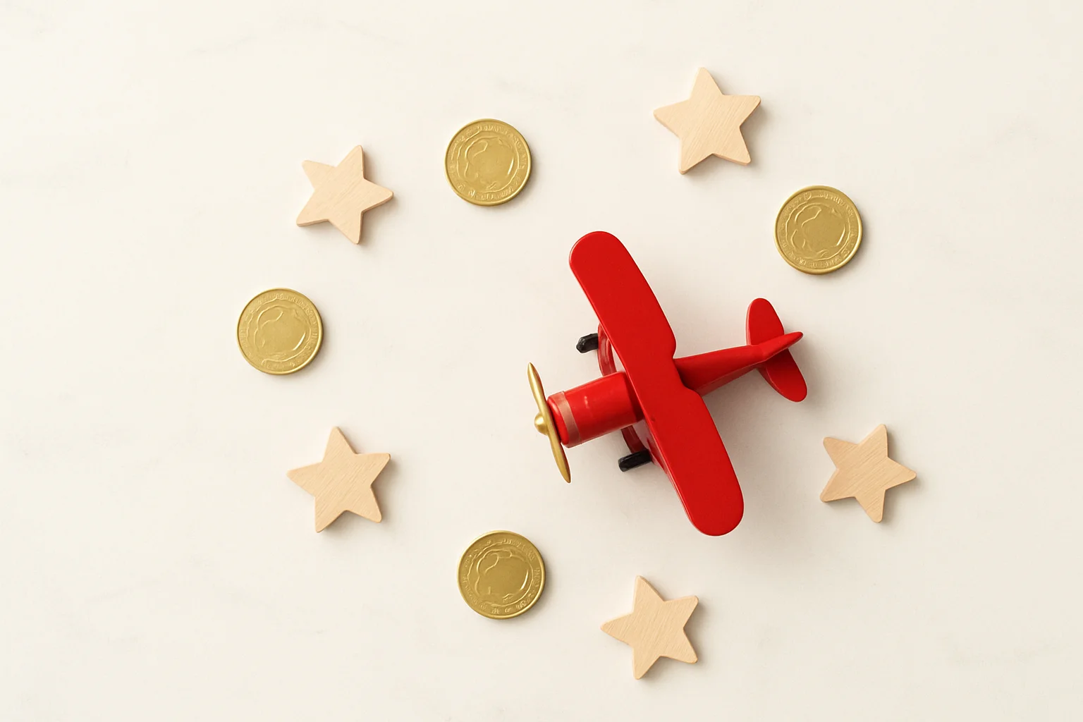 Red Airplane Tokens Miniature red airplane with gold coins and star tokens on marble